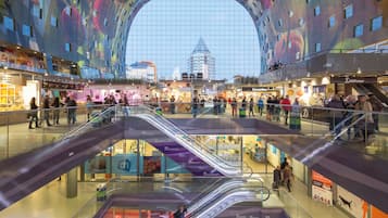 A multi-level shopping mall with escalators and a colorful ceiling design.