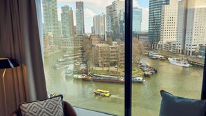 A view from a hotel room window overlooking a river with boats, tall buildings, and a clear sky. - Haven Hotel Rotterdam, Curio Collection by Hilton (Rotterdam)