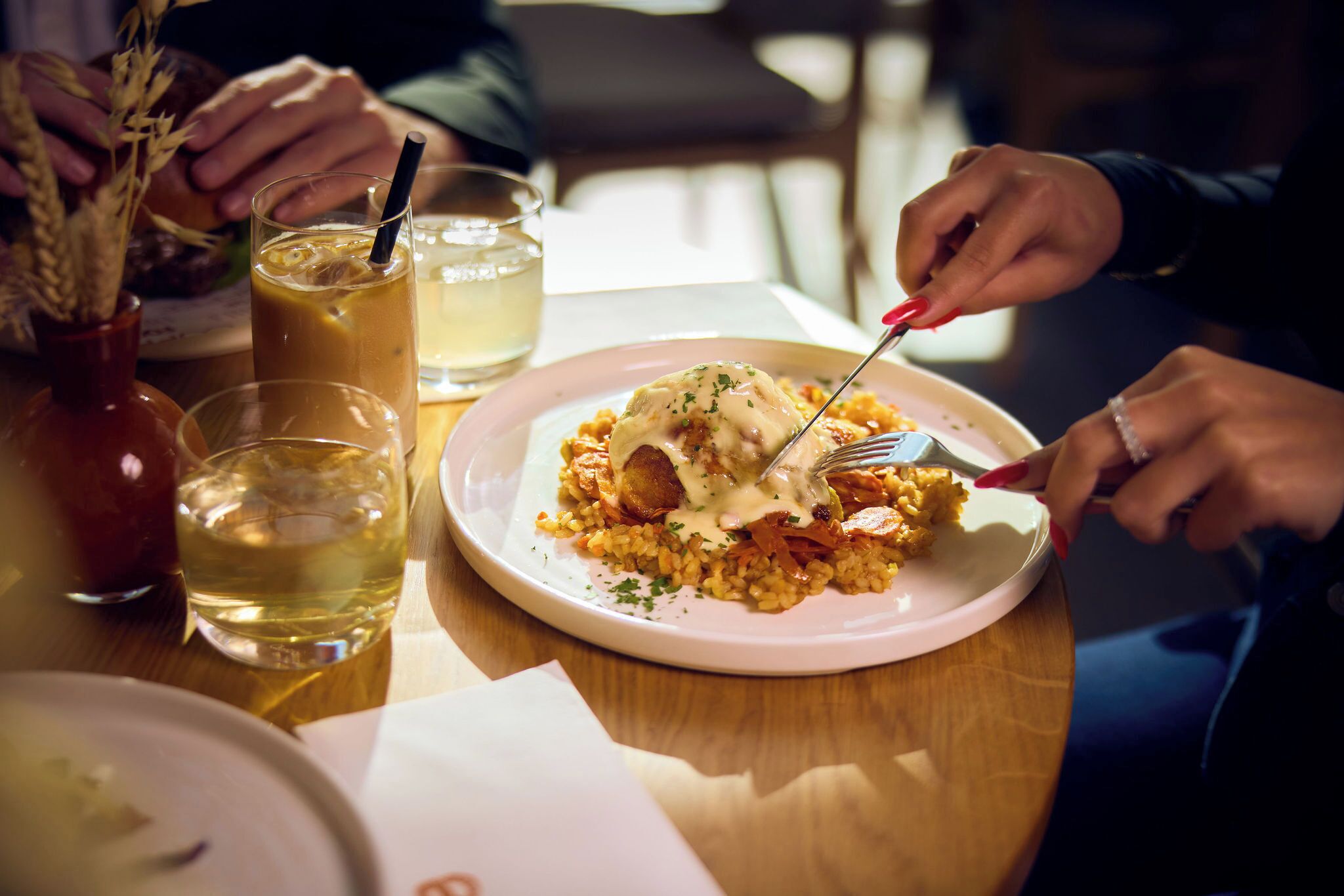 Ein Esstisch mit einem Teller Essen, einem Glas Getränk und einer Vase mit getrockneten Blumen.