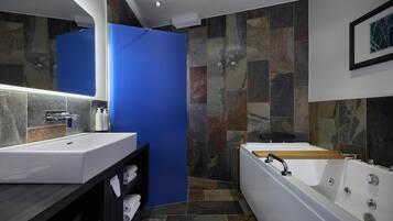 A modern bathroom with a large mirror, white sink, and bathtub.