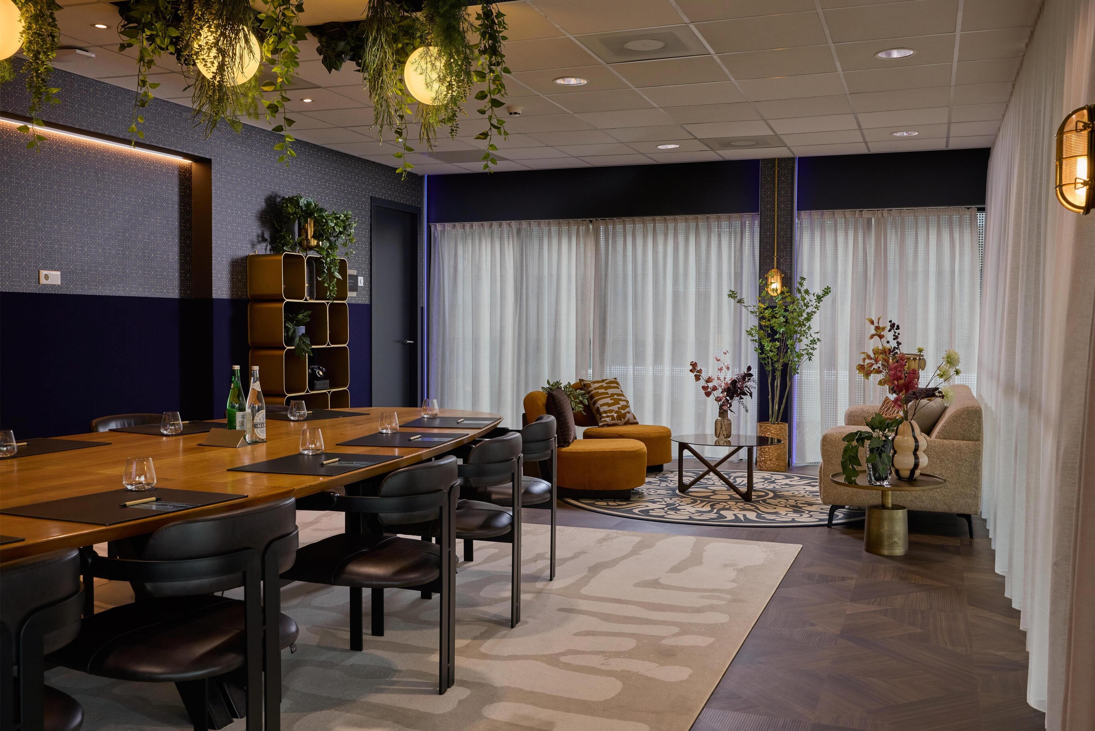 A modern conference room with a wooden table, black chairs, and a sofa.