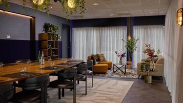 A modern conference room with a wooden table, black chairs, and a sofa.