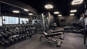 Un gimnasio moderno con varios equipos de levantamiento de pesas, cintas de correr y mancuernas.