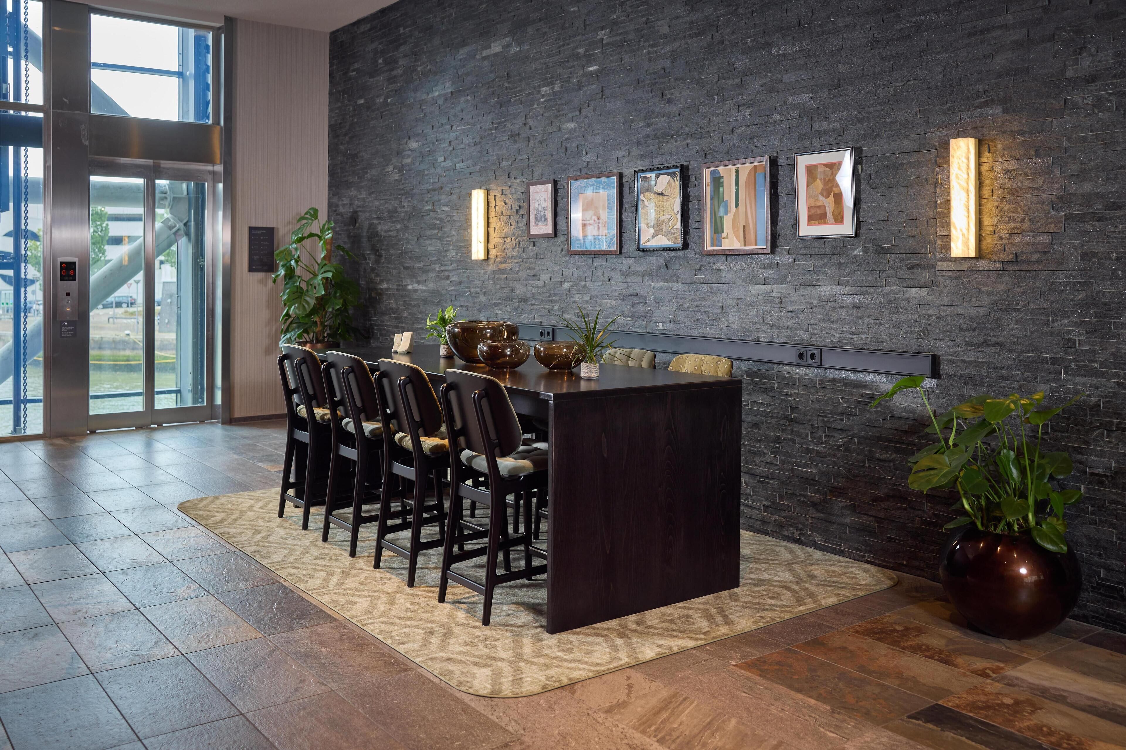 Un comedor moderno con una mesa de madera oscura, sillas y un jarrón grande con plantas verdes.