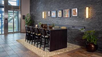 A modern dining area with a dark wood table, chairs, and a large vase of green plants.
