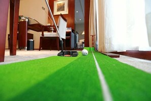 Un camp de mini golf amb una superfície de joc verda, una pilota de golf i un putter.