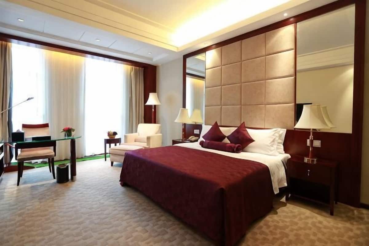 Une chambre d’hôtel avec un grand lit, des tables de chevet, un bureau et une chaise.