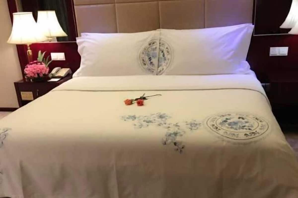 Une chambre d’hôtel avec un lit, une table de chevet avec une lampe et une couvre-lit à motifs floraux.
