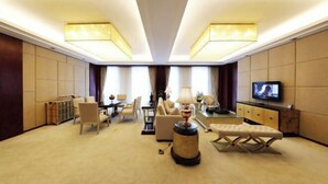 Amplia habitación de hotel con zona de estar amplia, televisión y mesa de comedor.
