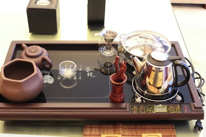 A tray with a teapot, cups, and a glass on a table.