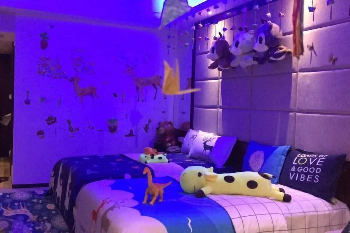 Une chambre à coucher avec un lit, des peluches et des décorations murales.