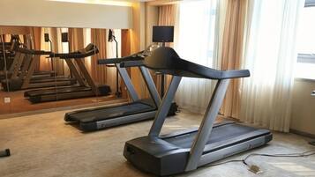 A hotel room with a treadmill, a large mirror, and a view of the outdoors.