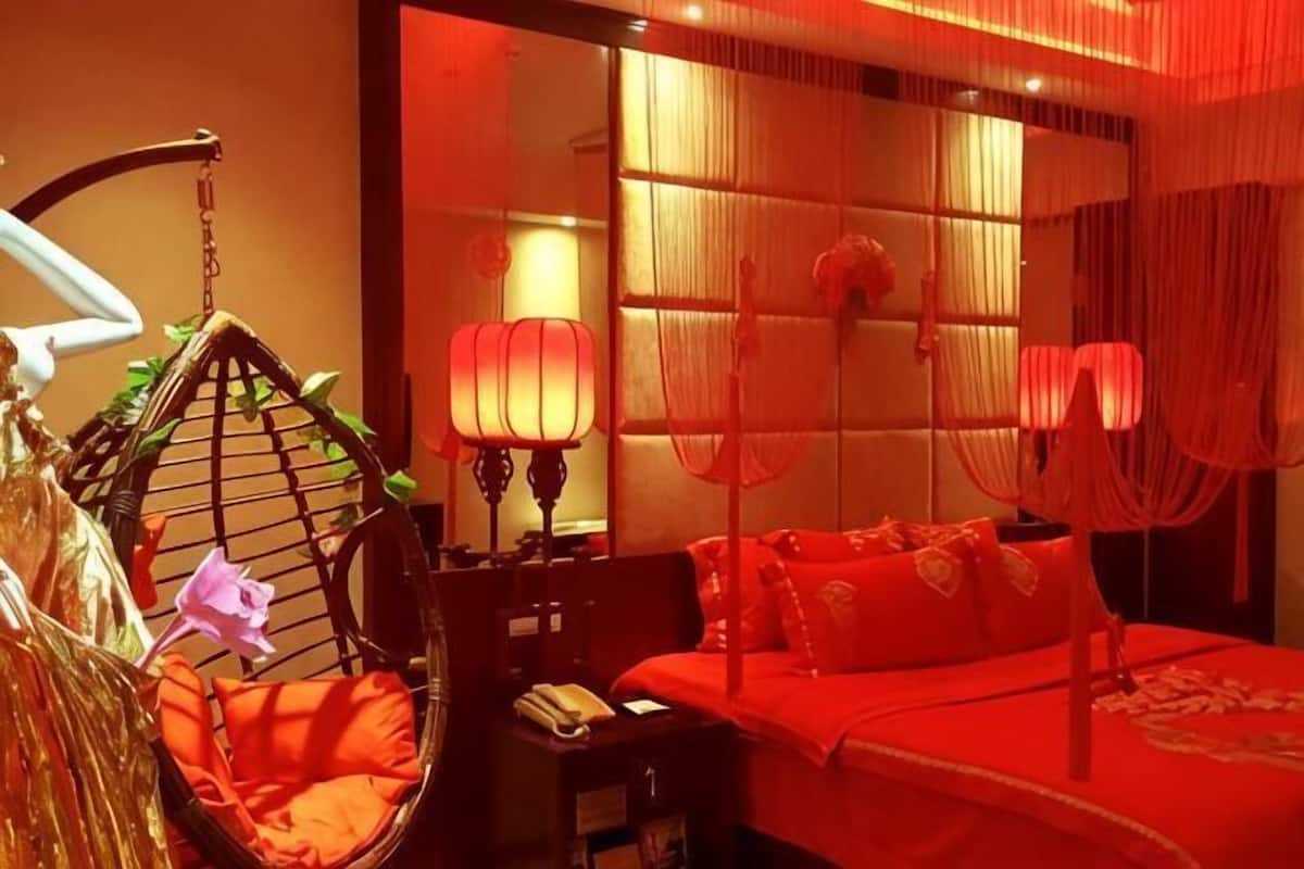 Une pièce comprenant un lit, un fauteuil suspendu, un bureau avec une lampe et une fenêtre avec des rideaux.