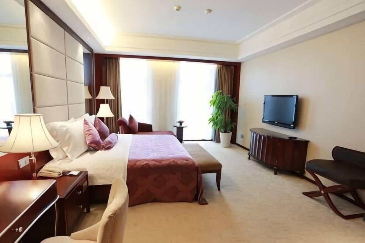 Une chambre d’hôtel avec un grand lit, des tables de chevet, une télévision, un bureau et une chaise.