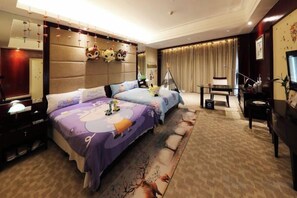 Habitación de hotel con dos camas, un escritorio, una silla, un televisor y un ventanal con cortinas.