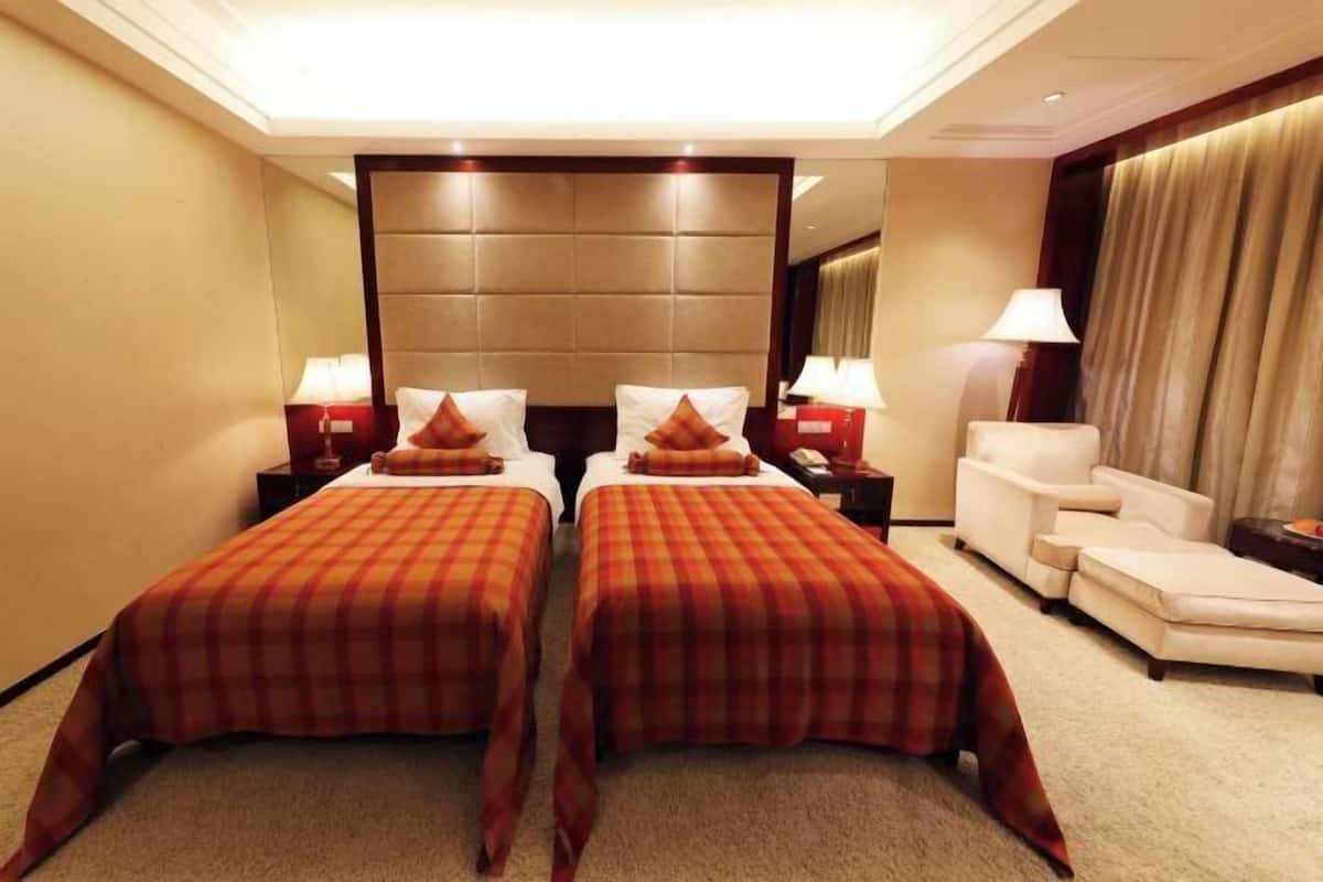 Une chambre d’hôtel avec deux lits, un canapé, une table de chevet et une lampe.