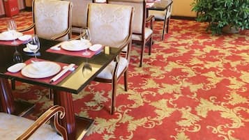 A dining area with tables set for four, each with chairs and tableware.