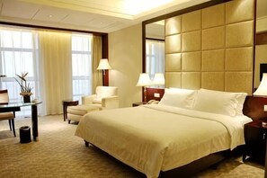 A hotel room with a large bed, two bedside tables, a desk, and a chair. - Jianghong International Hotel (Yongchuan)