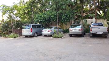 Un área de estacionamiento con cuatro vehículos, incluyendo una camioneta plateada, un sedán plateado y una camioneta pickup plateada.