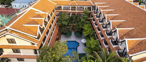 Un edificio de varios pisos con un patio central, balcones y una piscina.