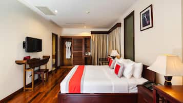 A hotel room with a large bed, bedside tables, a TV, a desk, and a wardrobe.