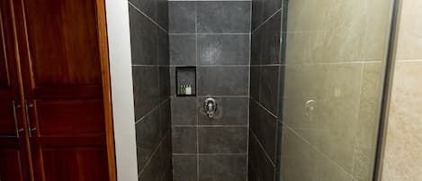 Un bagno con piastrelle scure, una doccia e una porta in legno.