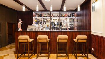 A bar area with wooden bar stools, a countertop with bottles, and a wooden ceiling with exposed beams.