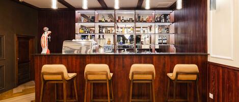 A bar area with wooden bar stools, a countertop with bottles, and a wooden ceiling with exposed beams.