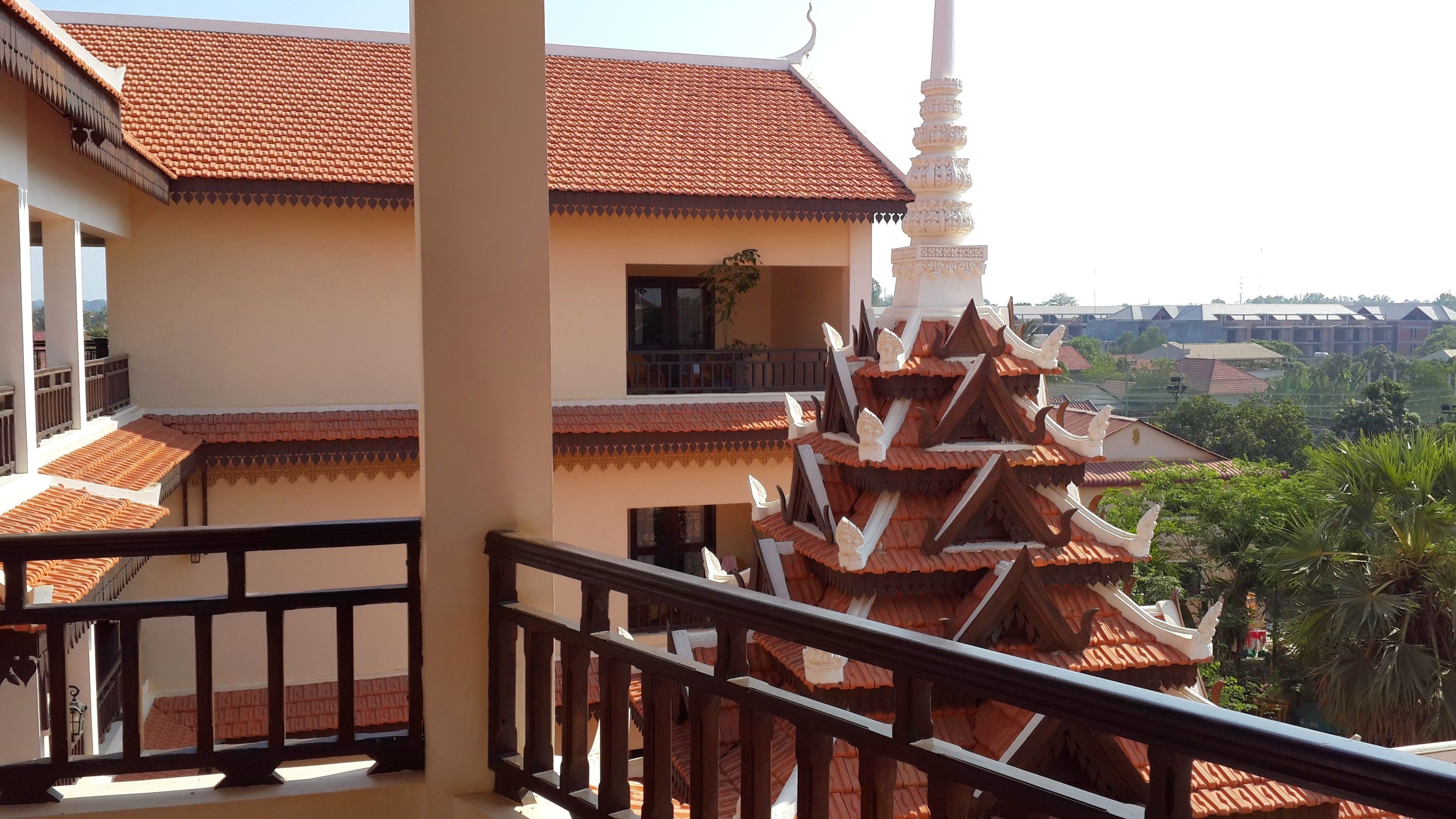 A traditional Thai building with a tiled roof and a tiered, ornate structure in the foreground.