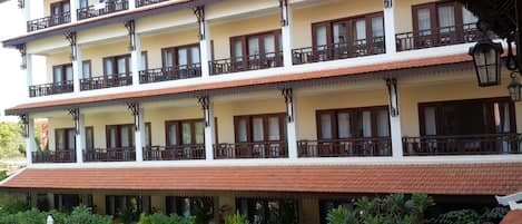 Un hotel de varios pisos con balcones, plantas en macetas y detalles arquitectónicos tradicionales.