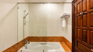 A bathroom with a glass-enclosed shower, a bathtub, and a wooden door.