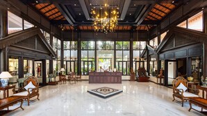 Un vestíbulo amplio con piso de mármol, un mostrador de recepción central y muebles de madera ornamentados.