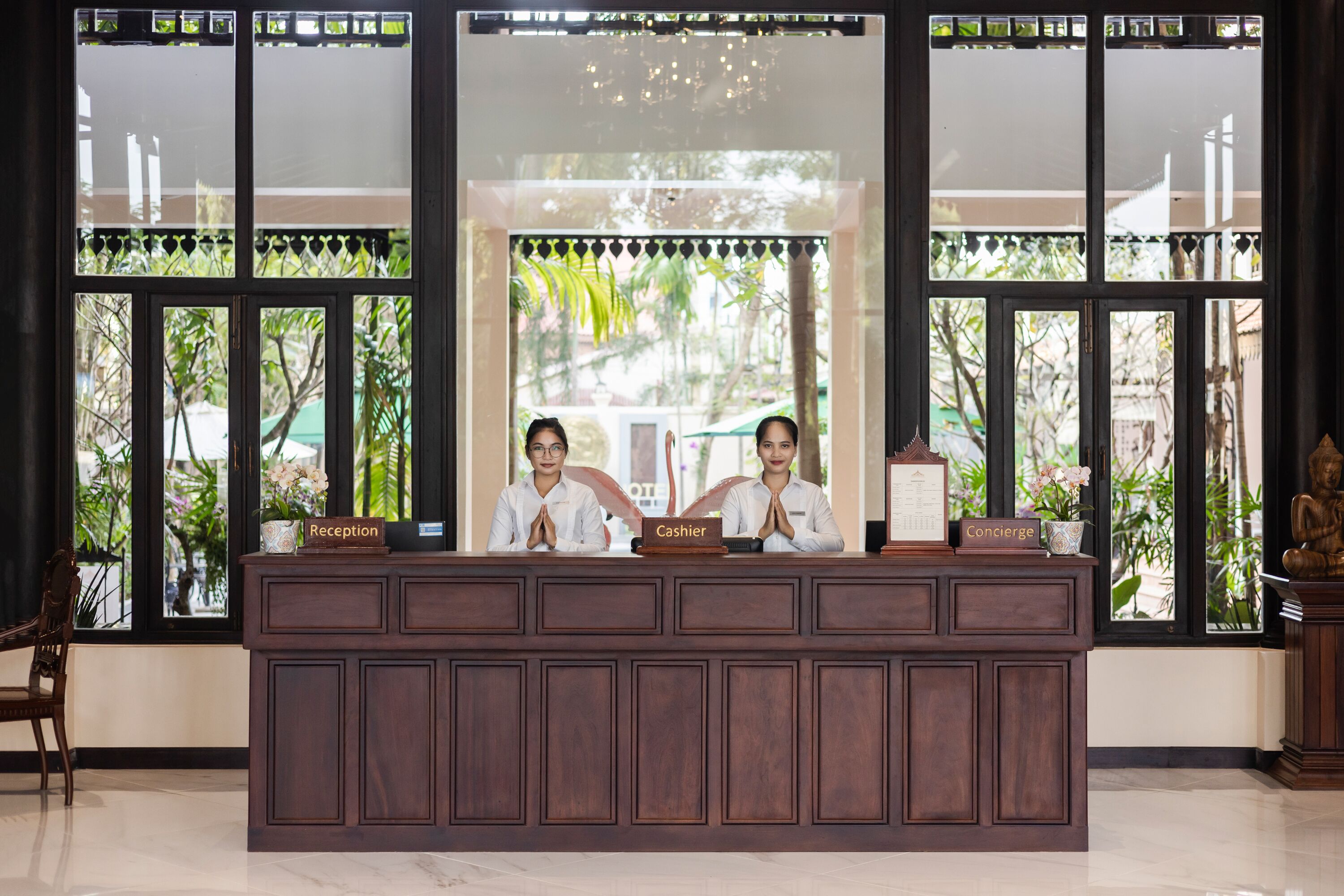 A reception desk with two staff members, a reception sign, a cashier sign, and a concierge sign.