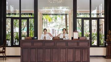 A reception desk with two staff members, a reception sign, a cashier sign, and a concierge sign.