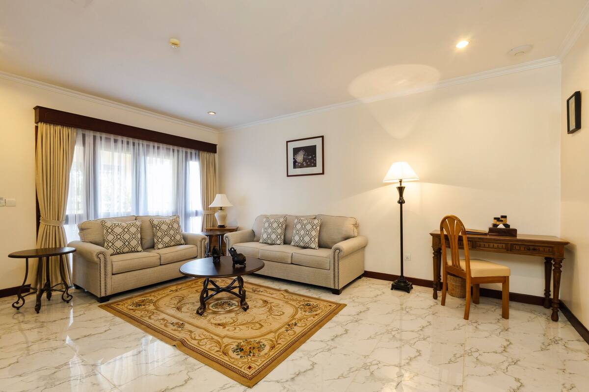 Un salon comprenant deux canapés, une table basse, une lampe, un bureau et une chaise.
