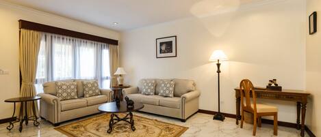A living room with two sofas, a coffee table, a lamp, a desk, and a chair.