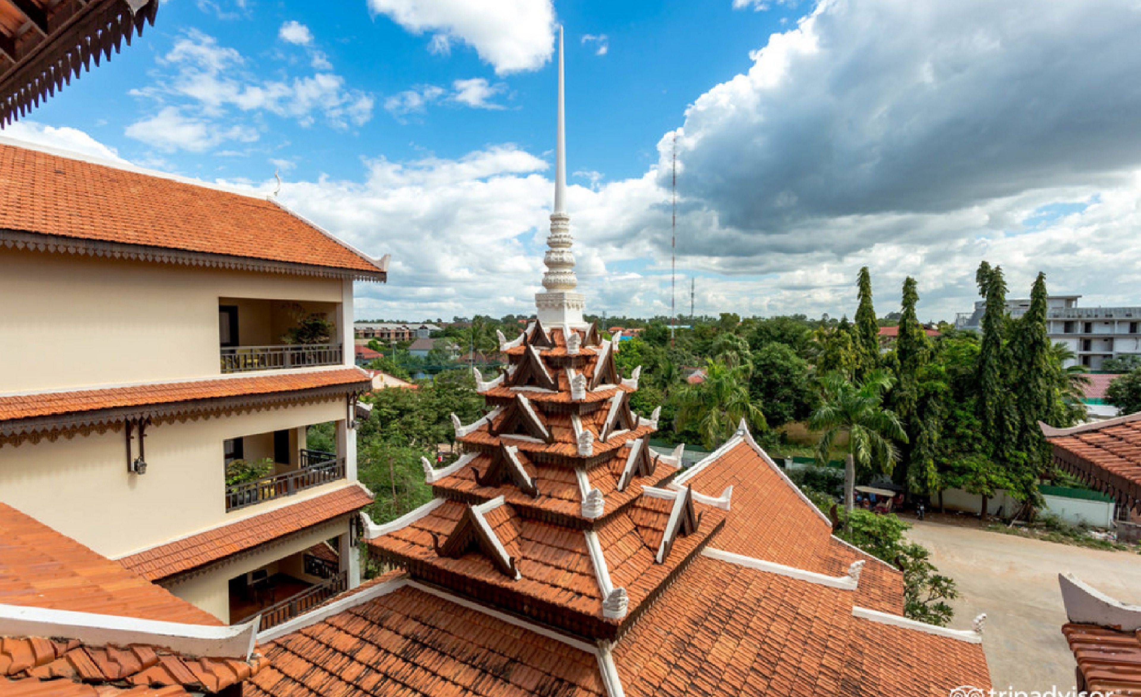 A traditional multi-tiered temple with a spire, surrounded by residential buildings and lush greenery.