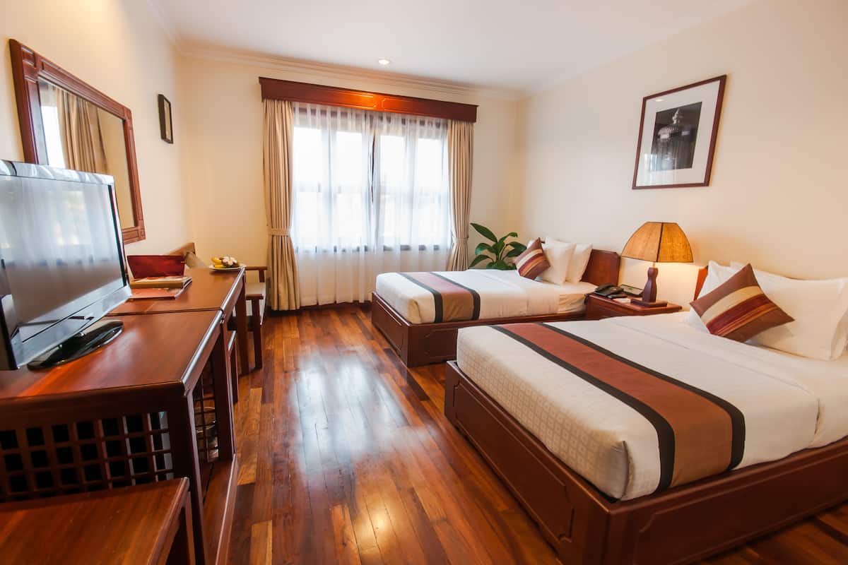Une chambre d’hôtel avec deux lits, une télévision et un bureau.