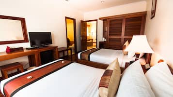 A hotel room with two beds, a desk with a television, a lamp, and a wardrobe.