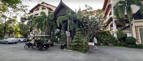 A traditional building with a pointed roof, surrounded by lush greenery and palm trees.