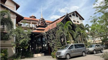 A traditional building with a multi-tiered roof and a modern car parked in front.
