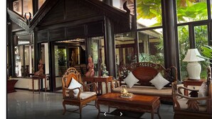 Un hall amplio con mobiliario de madera tradicional, ventanas grandes y plantas de interior.