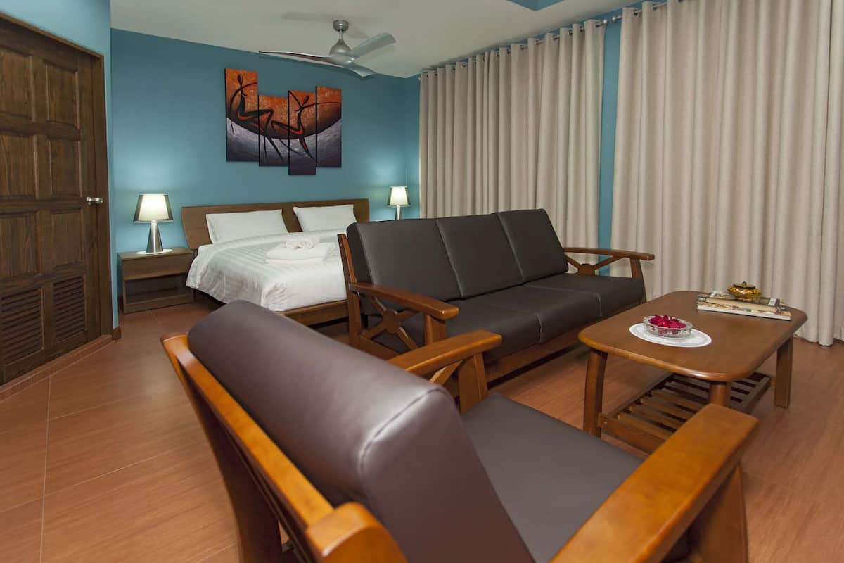 Une chambre d’hôtel avec un lit, un canapé, une table basse et un ventilateur de plafond.