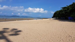 A beach with a clear sky, distant mountains, and a few people in the distance.