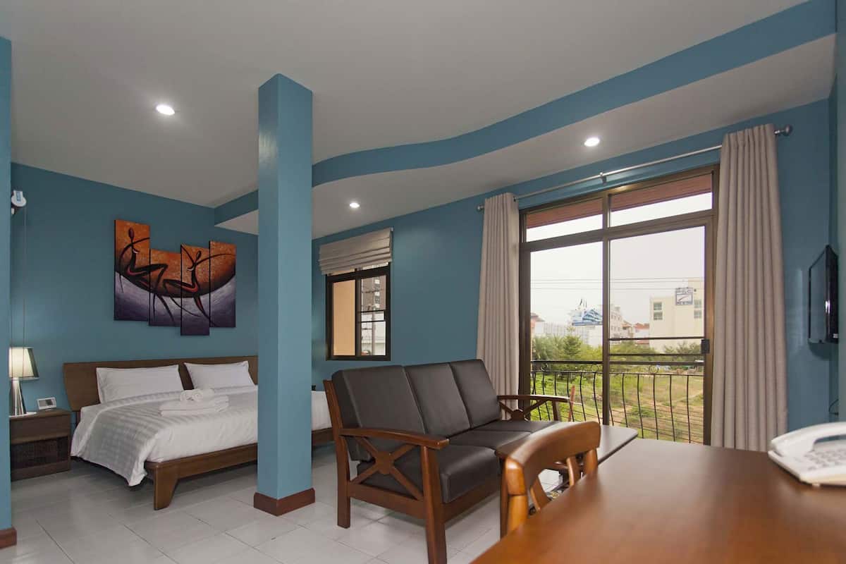 Une chambre d’hôtel comprenant un lit, un canapé, une table à manger, une télévision et une fenêtre donnant sur des immeubles.