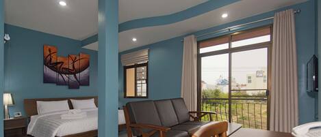 A hotel room with a bed, a sofa, a dining table, and a large window with a view.