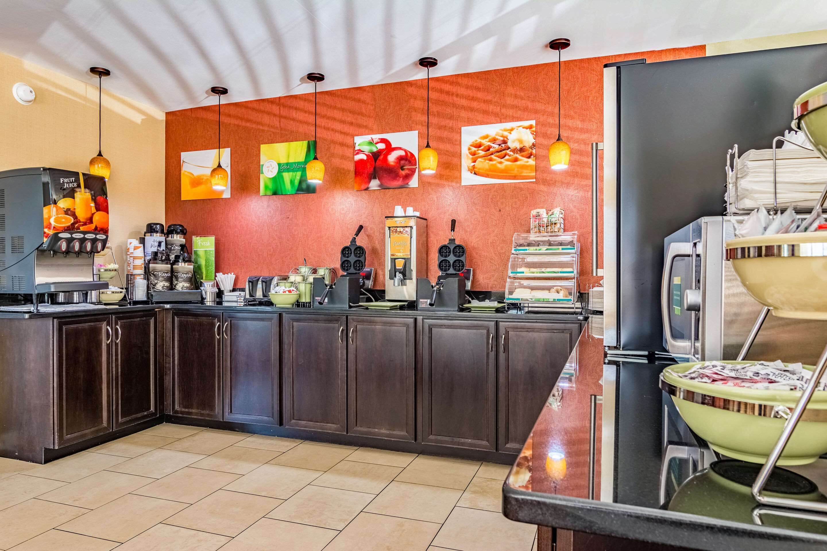 Una cocina moderna con armarios de madera oscura, una estación de café y un dispensador de zumo de frutas.