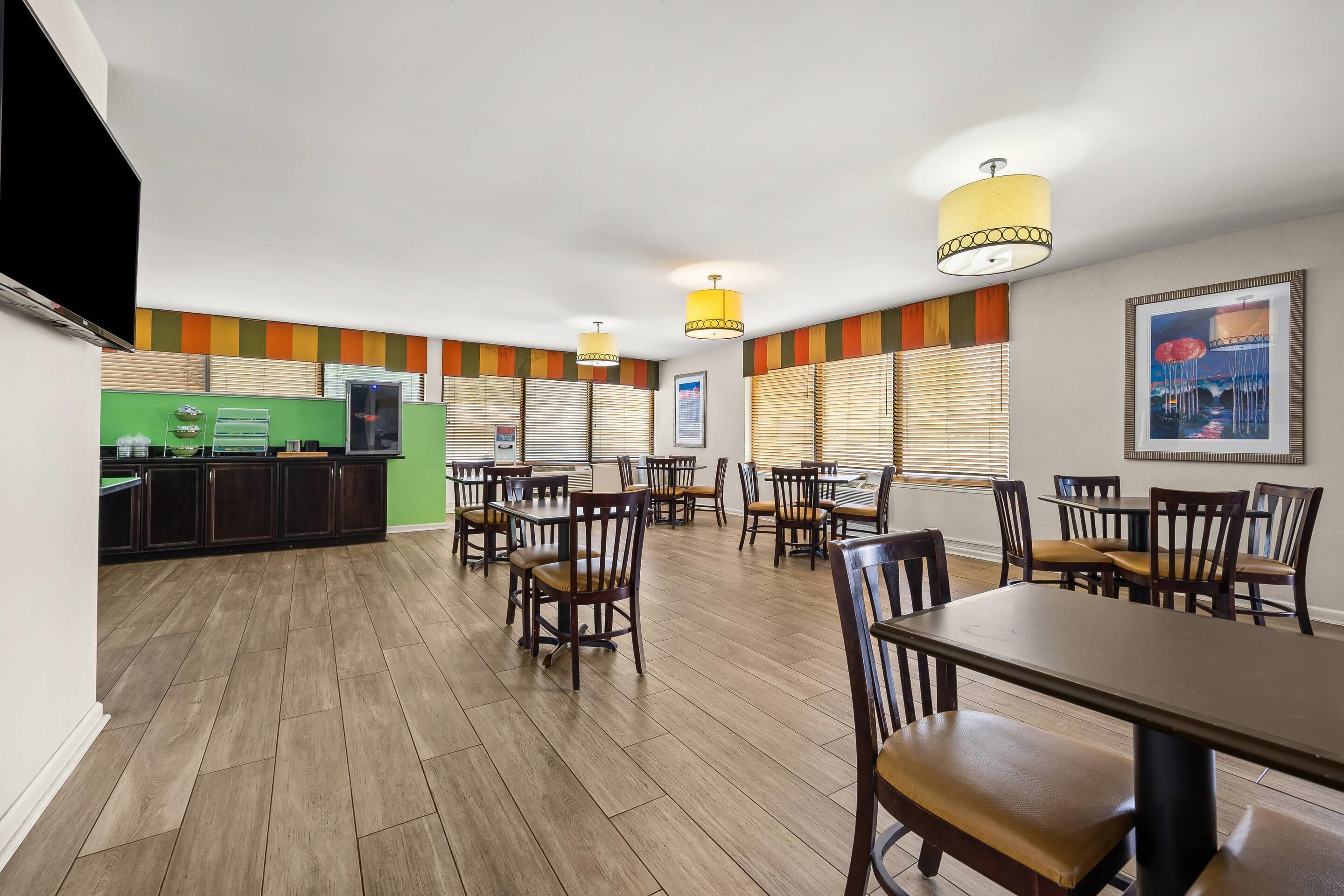Un espace repas doté d’un plancher en bois, de tables, de chaises et d’un comptoir vert.