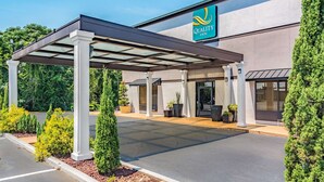 A covered outdoor area with a canopy, a building with a 'Quality Inn' sign, and potted plants.