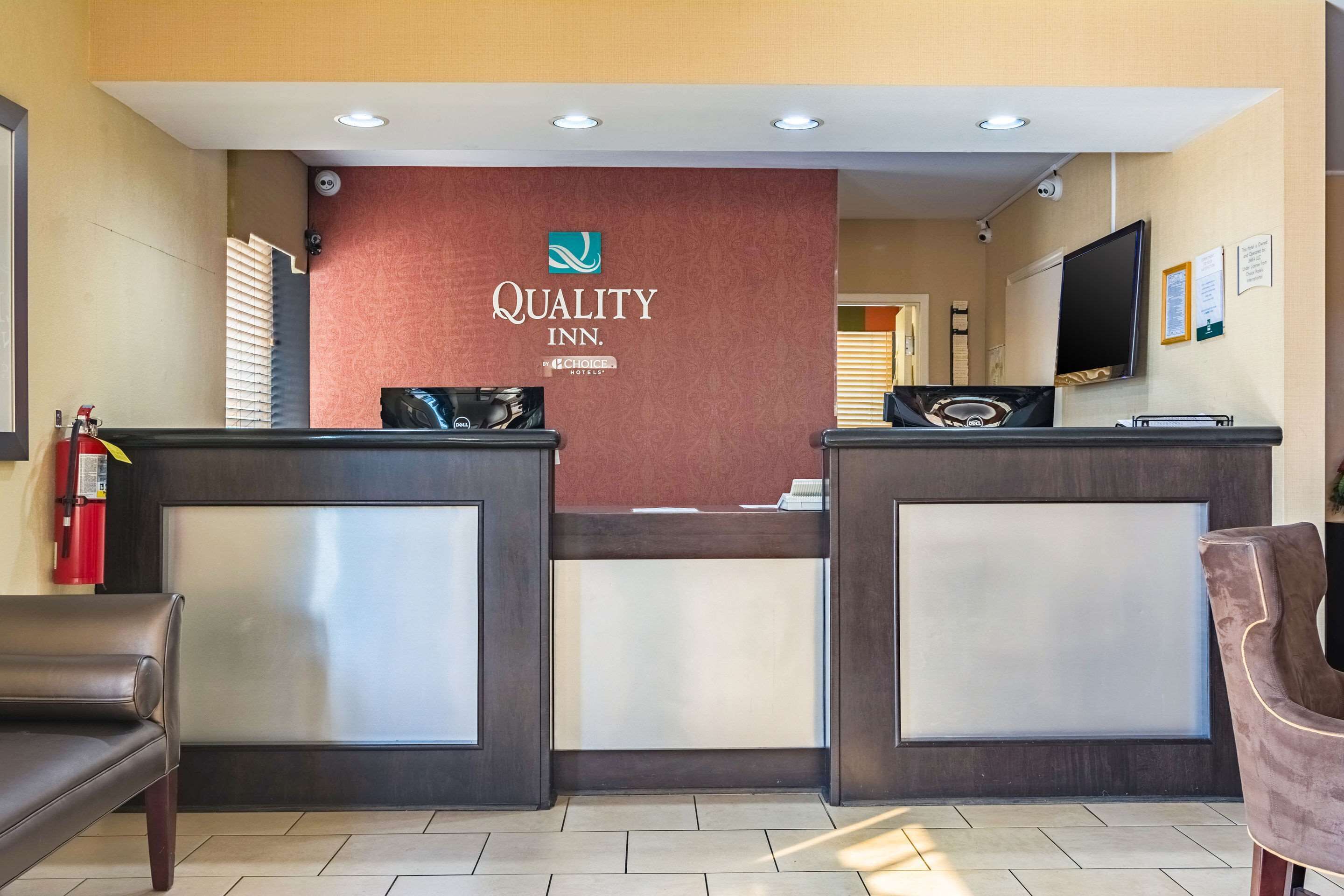 A hotel reception area with a reception desk, a television, and a fire extinguisher.